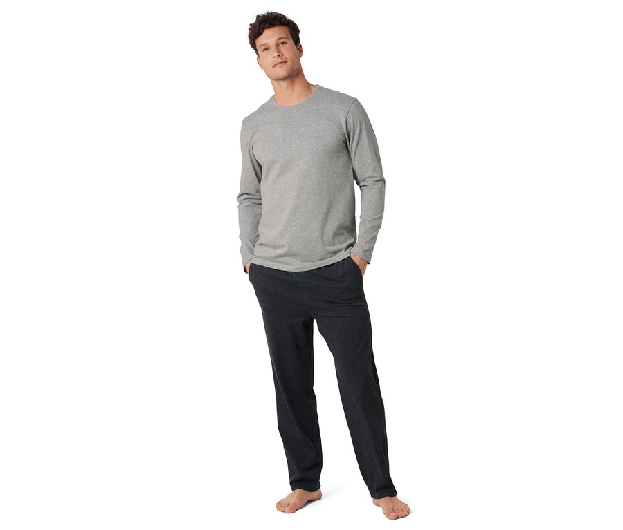 Mann posiert in grauem Pyjama-Oberteil und dunkler Hose aus einem 4-teiligen Pyjama-Set.