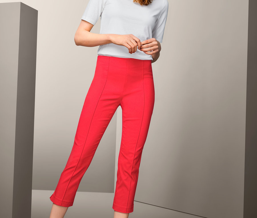 Frau posiert in roter 7/8-Stretchhose und weißem T-Shirt.