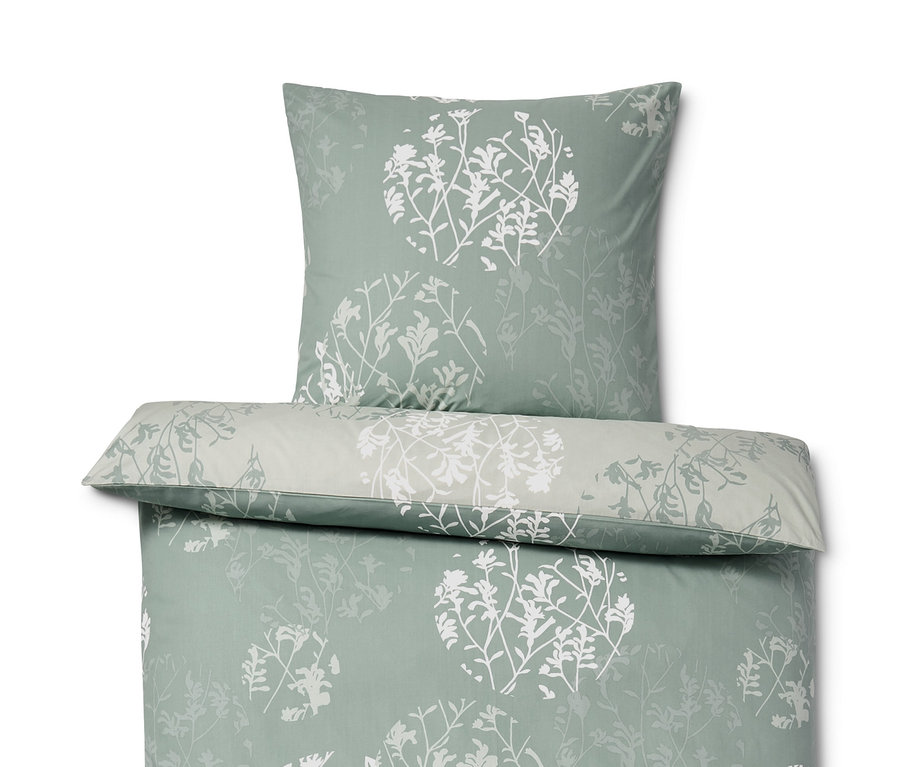 Gezeigt wird Renforcé-Bettwäsche in Normalgröße mit einem Muster aus weißen Blumen auf grünem Hintergrund.