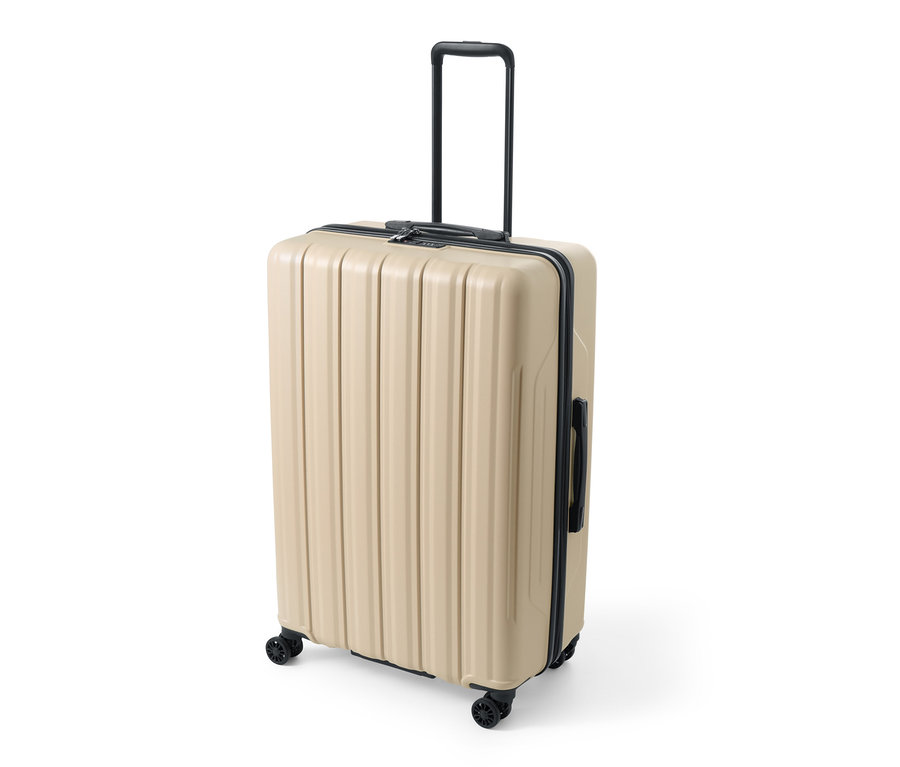 Ein großer, beiger Hartschalen-Koffer mit recyceltem Material steht auf Rollen, der Griff ist ausgefahren.