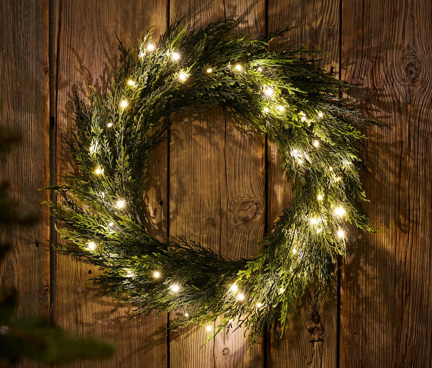 An einer Holzwand hängt ein LED-Dekokranz.