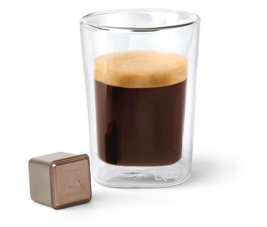 Kaffee in einem Glas neben einer Qbo Caffè Grande BELO SUL Kapsel.