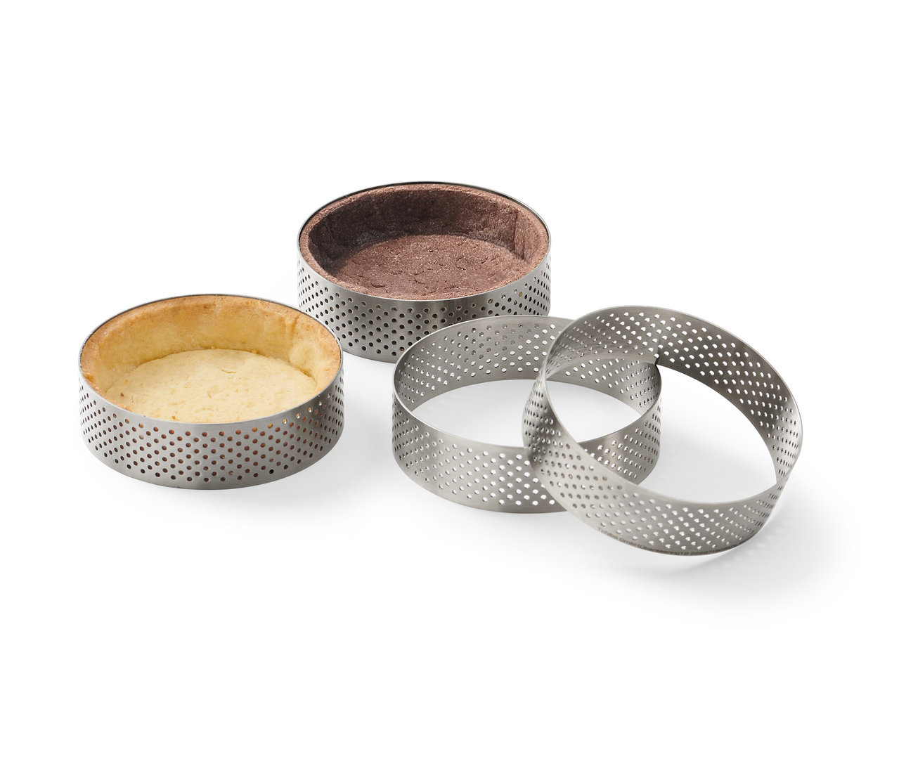 Vier Edelstahl-Backringe, zwei davon mit gebackenem Teig.