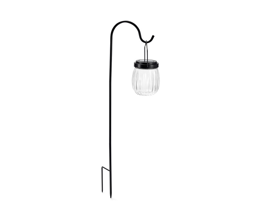 Eine Spieß-Solar-Leuchte mit einem klaren, gerippten Lampenschirm hängt an einem Bogen.