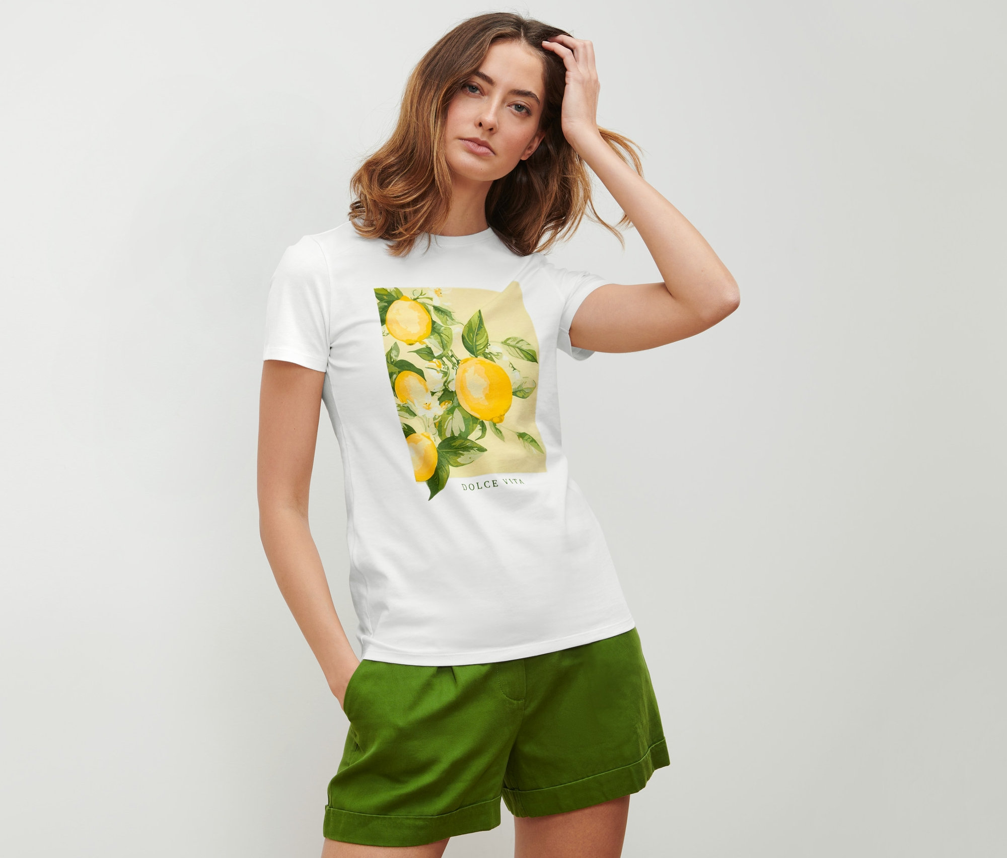 Frau posiert in einem T-Shirt mit Print und grünen Shorts.