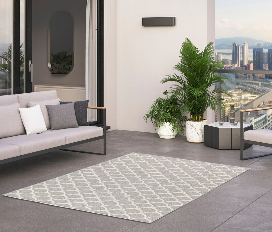 Terrasse mit Sofa mit Kissen, Sessel und zwei Outdoor-Teppichen Arcs.