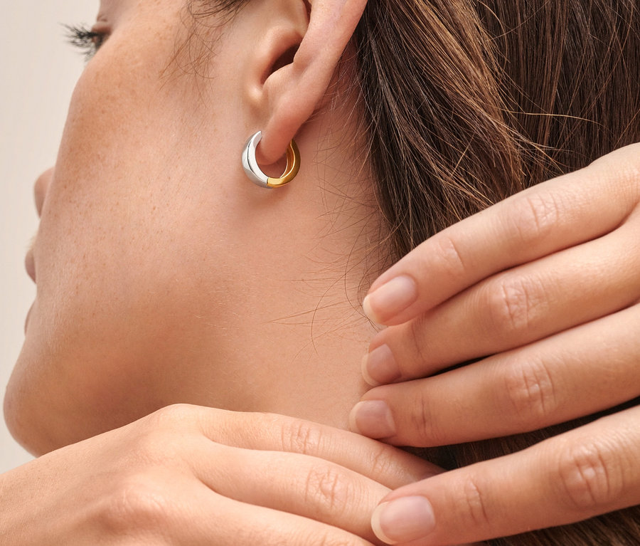 Nahaufnahme einer Frau, die Creolen, 925 Silber bicolor, wendbar, trägt.