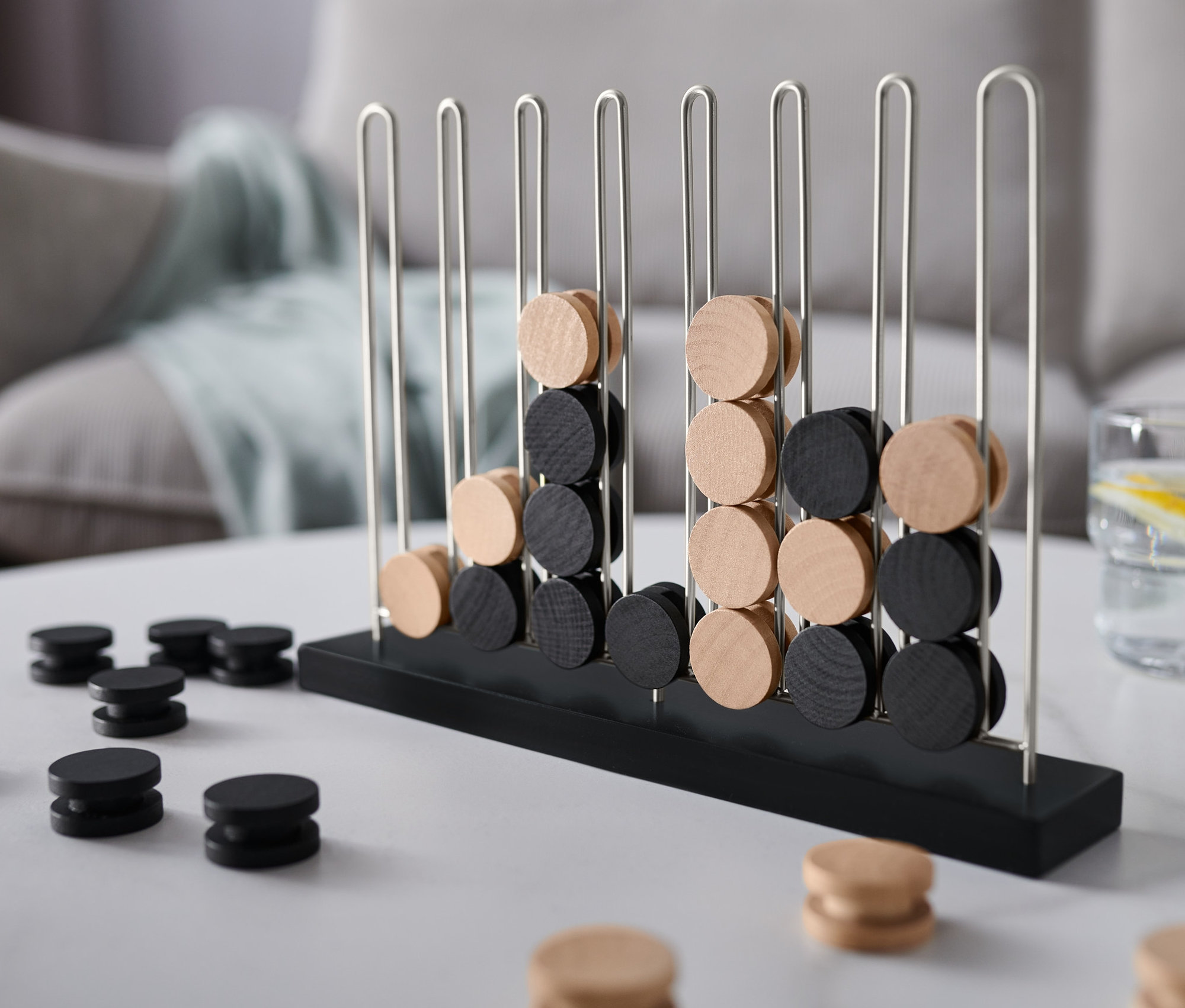 Ein schwarz-beiges Spiel »4 in einer Reihe« steht auf einem Tisch.