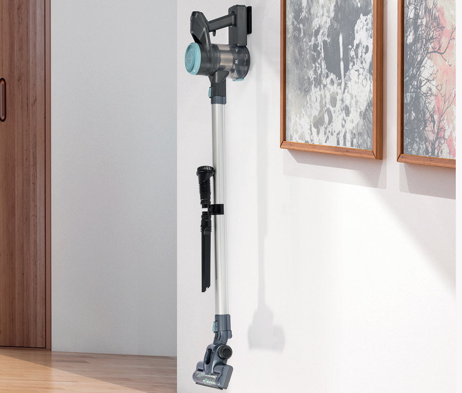 Ein grauer Akku- Hand- und Bodenstaubsauger hängt an einer weißen Wand.