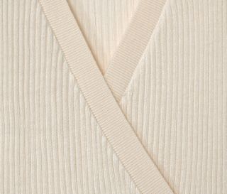 Nahaufnahme einer cremefarbenen Kinder-Strickjacke.