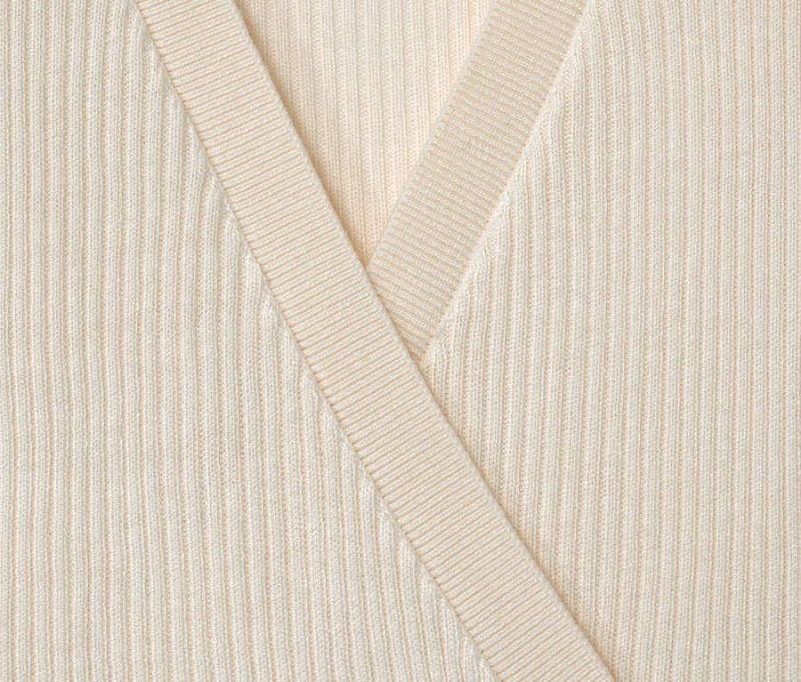 Nahaufnahme einer cremefarbenen Kinder-Strickjacke.