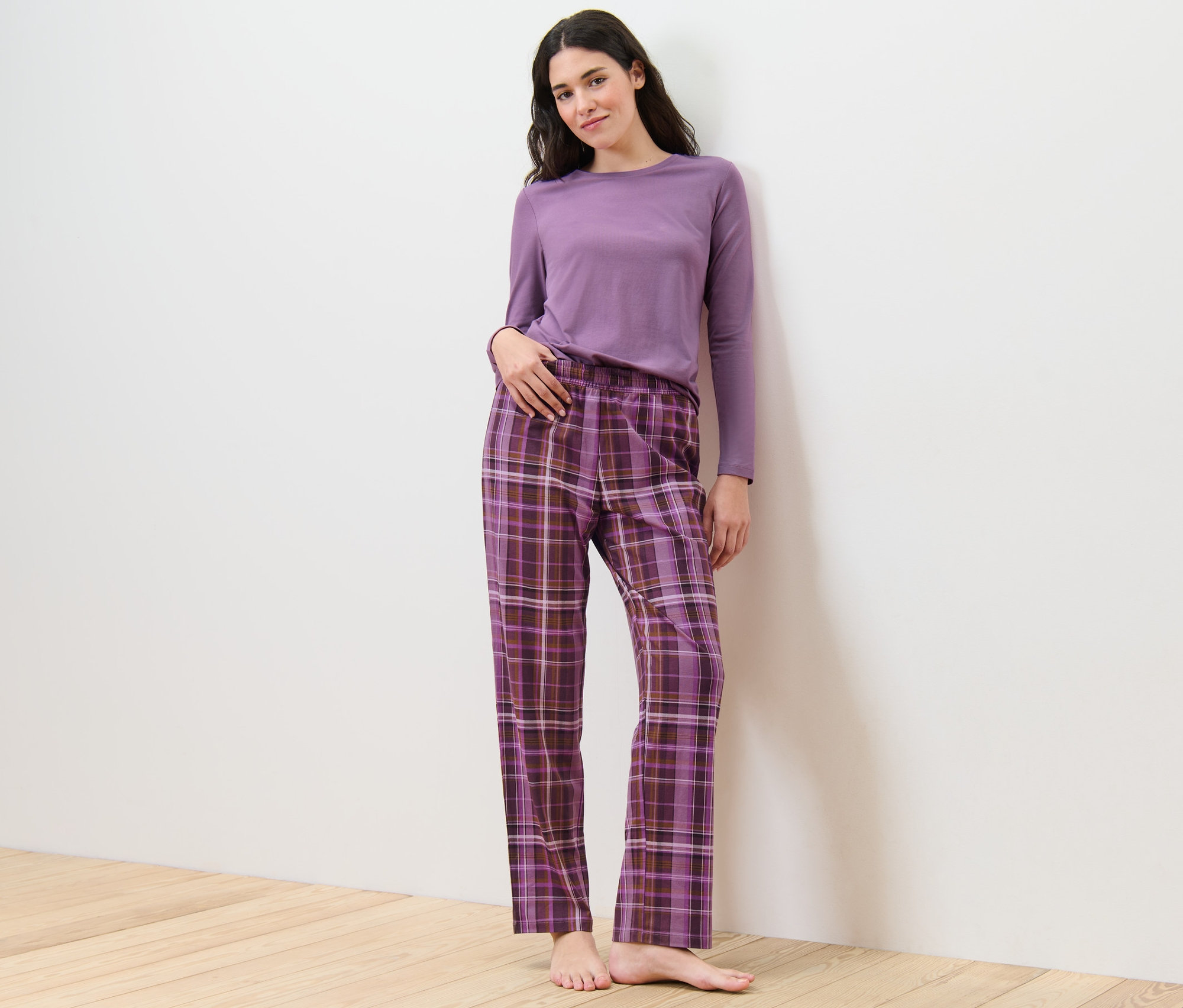 Frau posiert in Pyjama mit karierter Hose.