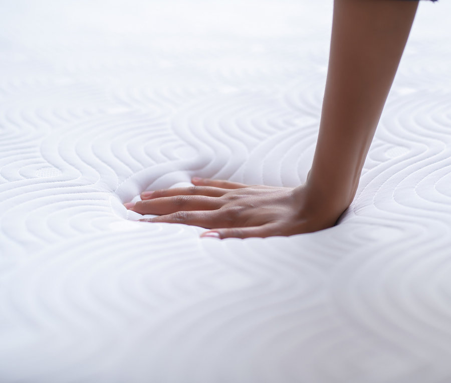 Eine Hand berührt eine weiße TEMPUR® ONE™ Matratze.