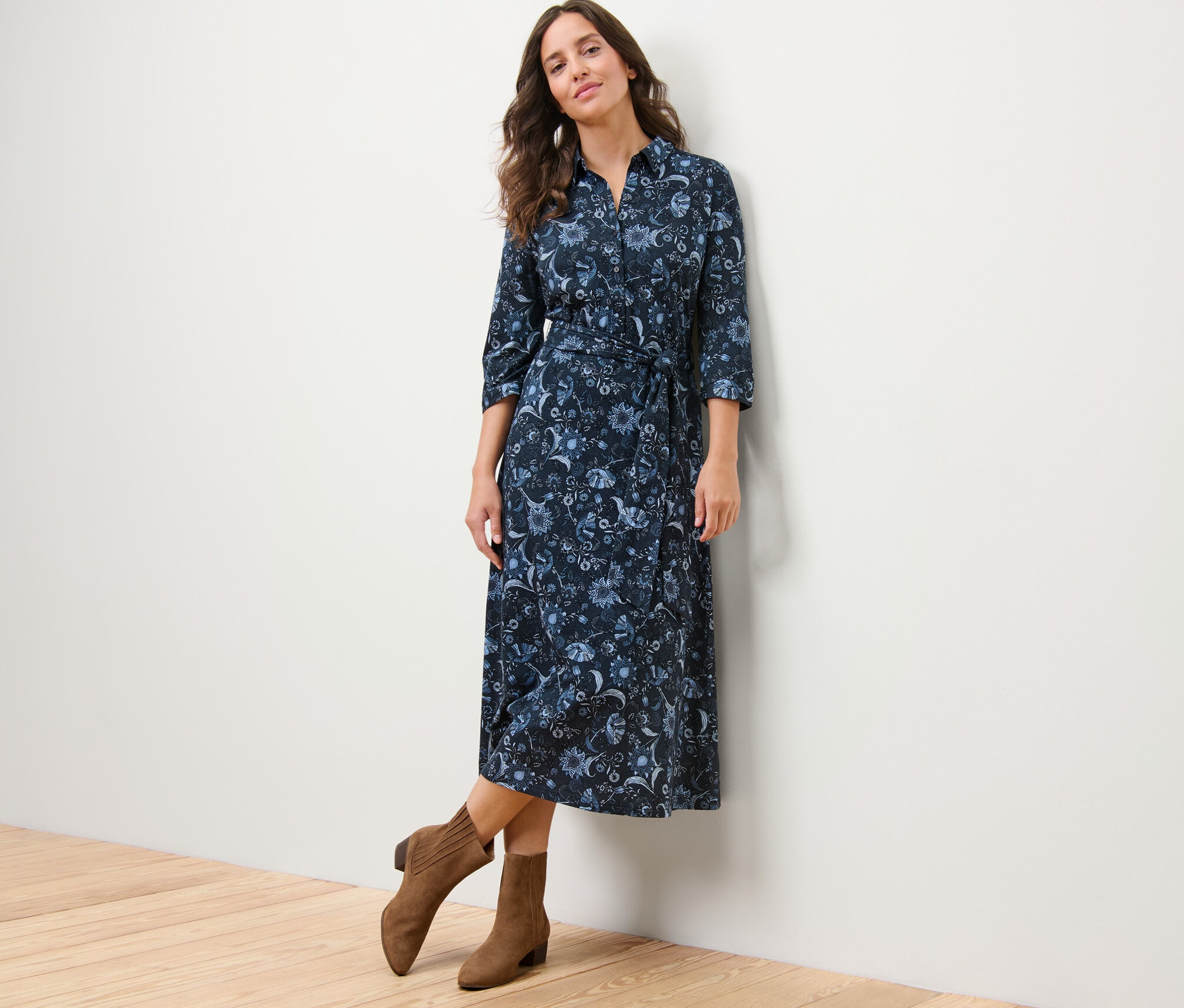 Frau posiert in einem bedruckten Jerseykleid und braunen Stiefeln.