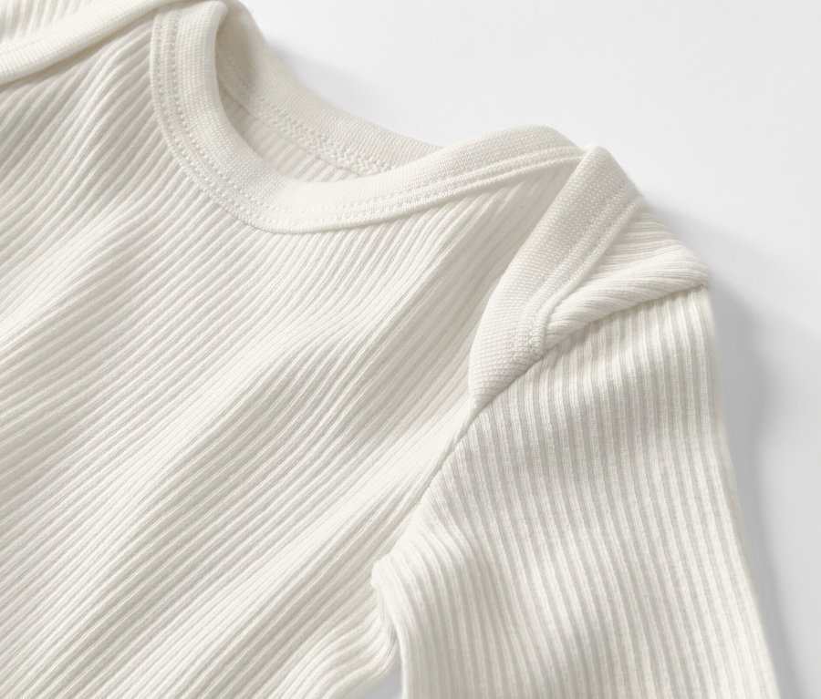 Detailaufnahme eines gerippten Baby-Langarmbodys.
