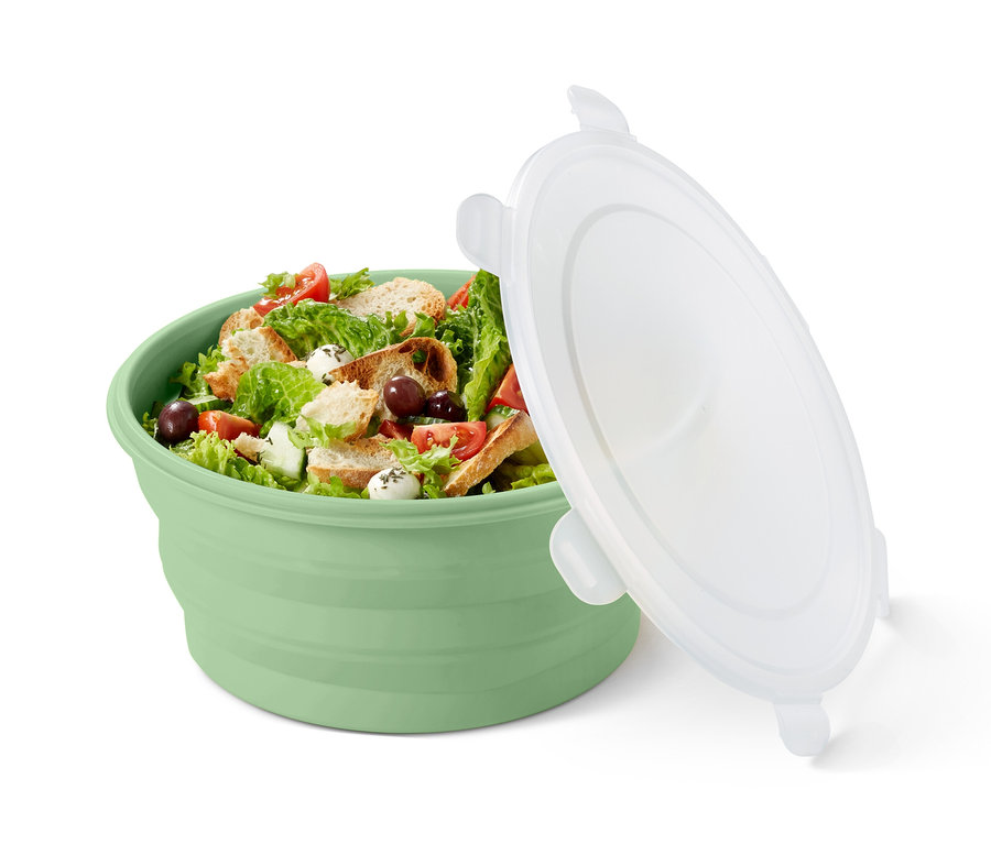 Eine grüne faltbare Salatschüssel gefüllt mit Salat und einem weißen Deckel.