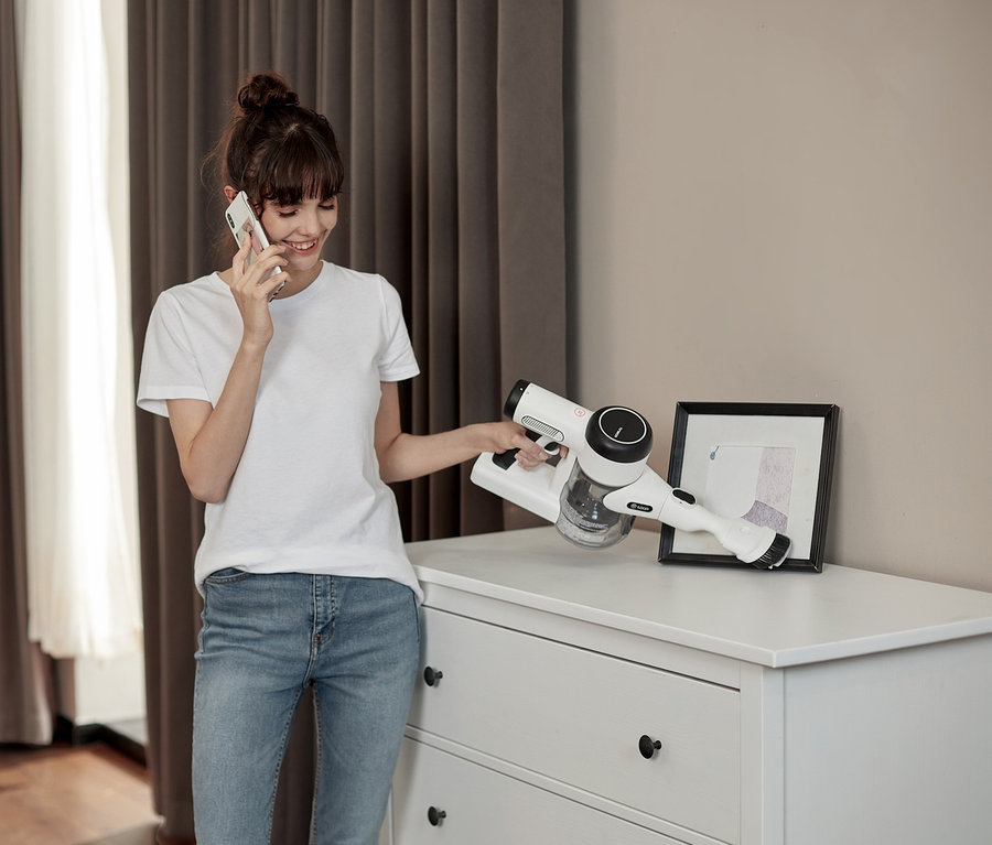 Frau telefoniert und hält einen Tineco Pure One x Essentials Akkusauger.