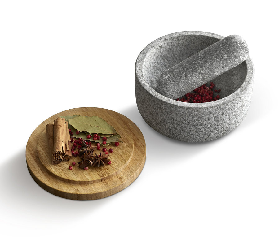 Gewürze auf einem Holzbrett neben einem Joseph Joseph Granit Mörser »Dash«.