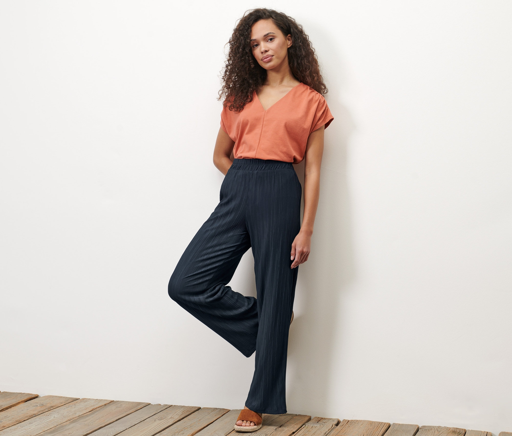 Frau posiert in dunkelblauer Plisseehose.