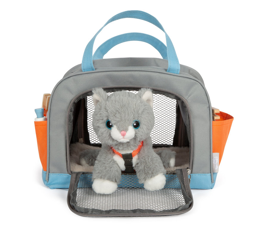 Eine graue Stoffkatze sitzt in einer grauen Tasche mit blauen Griffen und orangefarbenen Seitentaschen, es handelt sich um die small foot Katze mit Tasche und Pflege-Set.