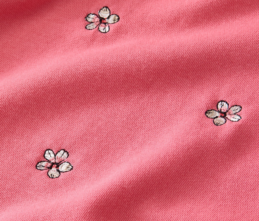 Detailaufnahme eines rosafarbenen, bestickten Sweatshirts.