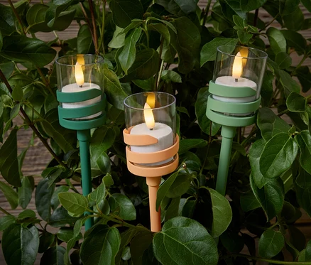 Drei LED-Outdoor-Spieße inmitten von grünen Blättern. Zwei sind grün, einer ist pfirsichfarben.