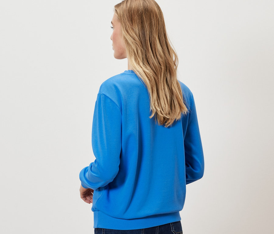 Frau von hinten trägt kobaltblaues Sweatshirt.