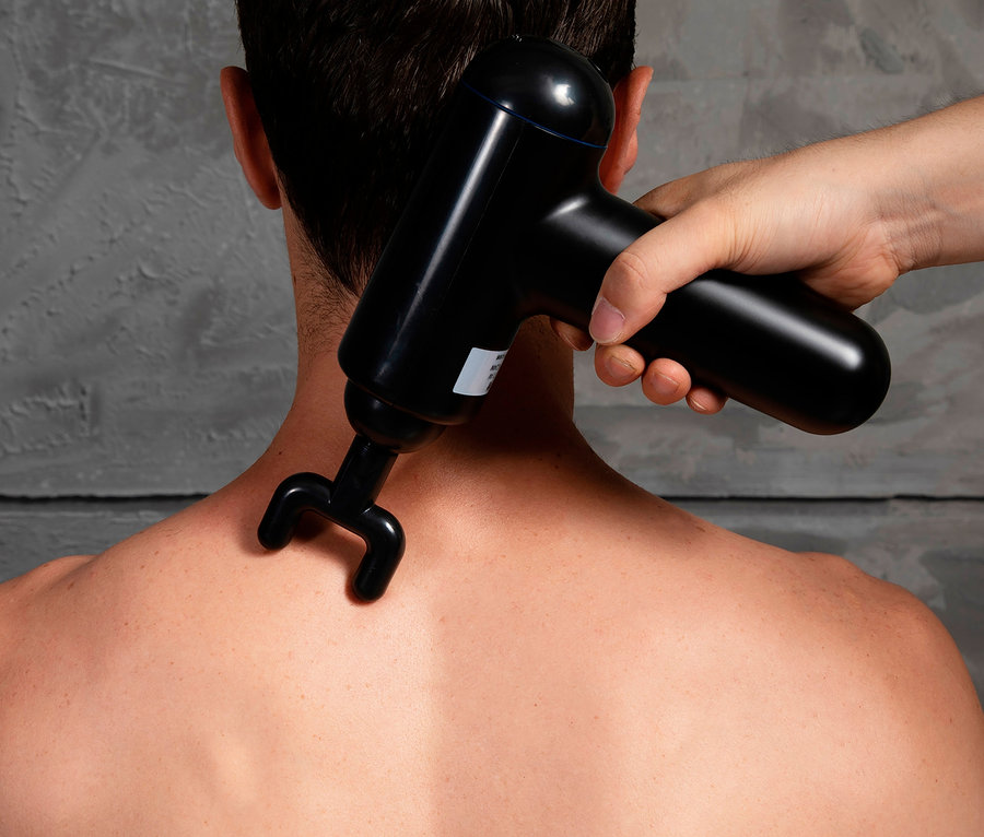 Jemand massiert den Rücken einer Person mit einer MELISSA Infinity Massagepistole.