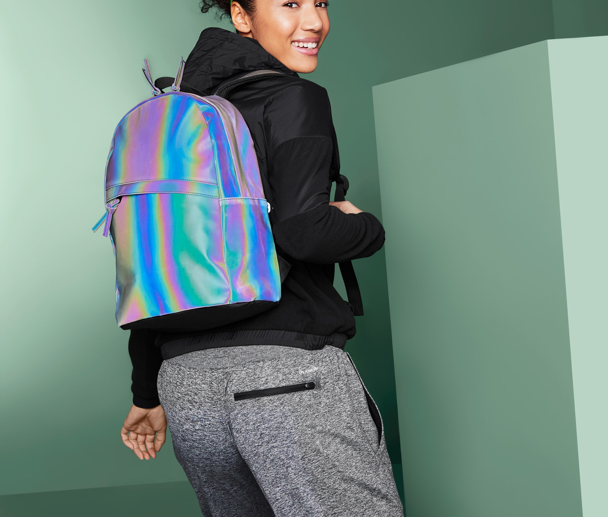 Frau blickt über die Schulter und trägt einen reflektierenden Rucksack.