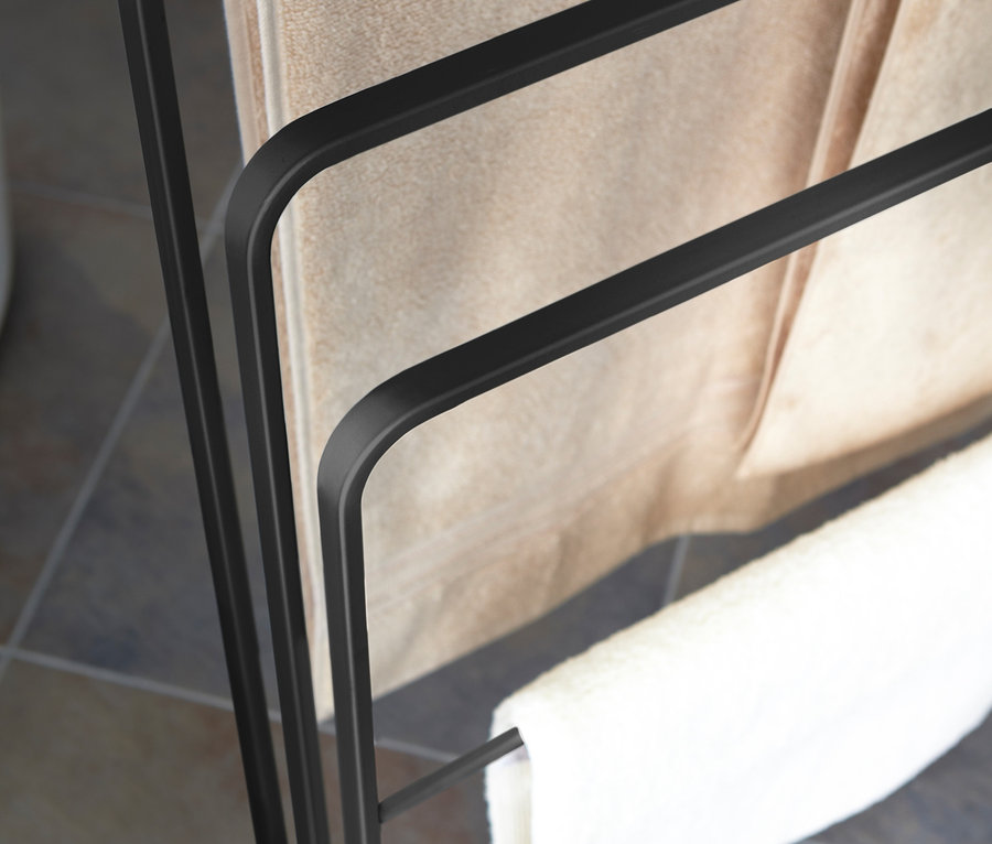 Schwarzer YAMAZAKI Badehandtuch-Ständer »TOWER« mit zwei beigen und einem weißen Handtuch.