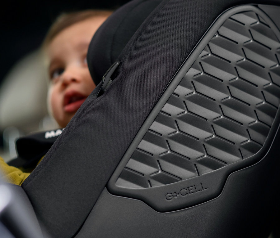 Detailaufnahme eines schwarzen Maxi-Cosi Kinder-Autositzes »Mica 360 S« mit einem Kind im Hintergrund.