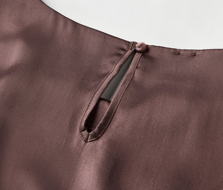 Detail eines braunen Satintops mit Schlüssellochausschnitt und Knopfverschluss im Nacken.