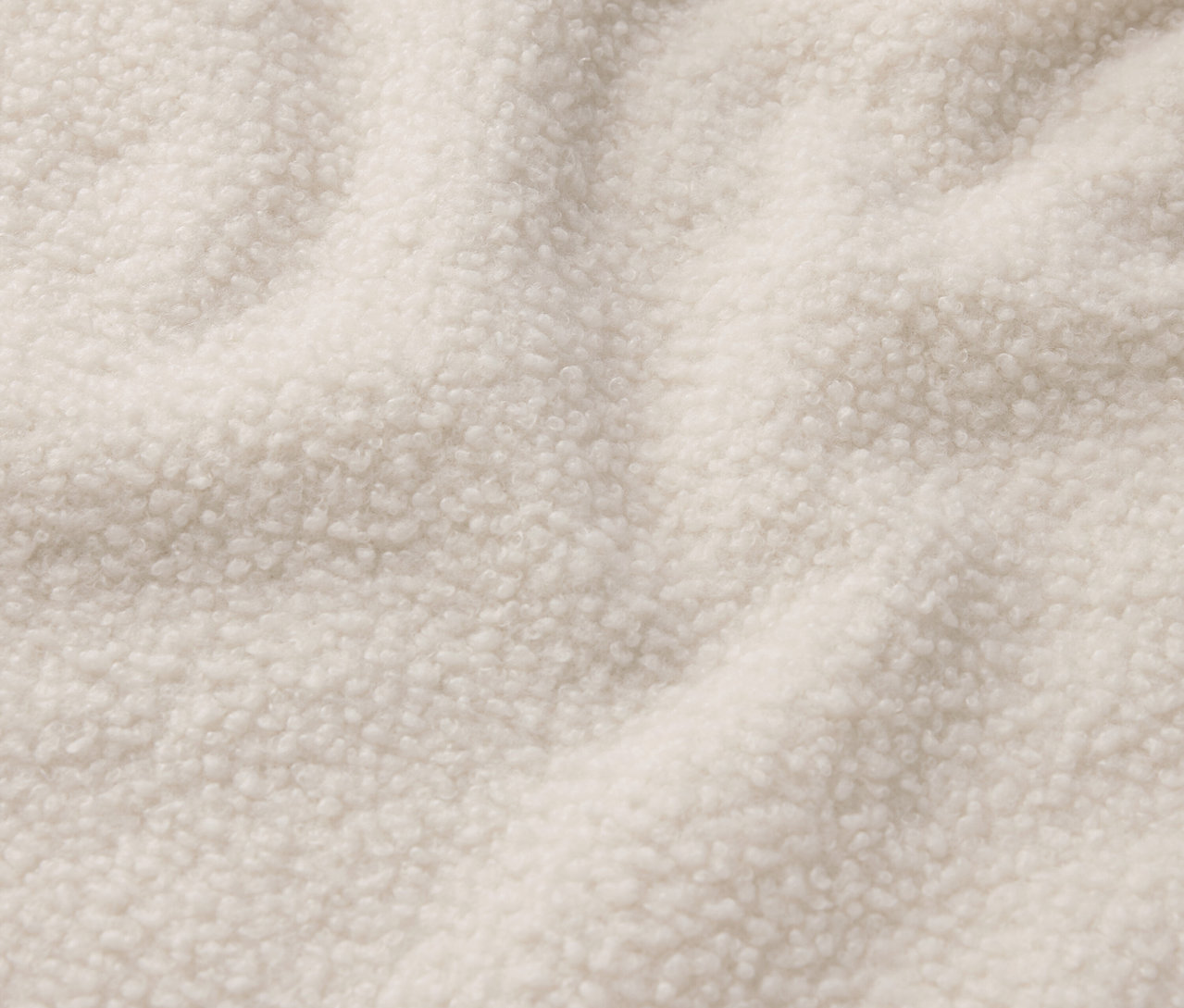 Detailaufnahme eines cremefarbenen Shearling-Stoffs.