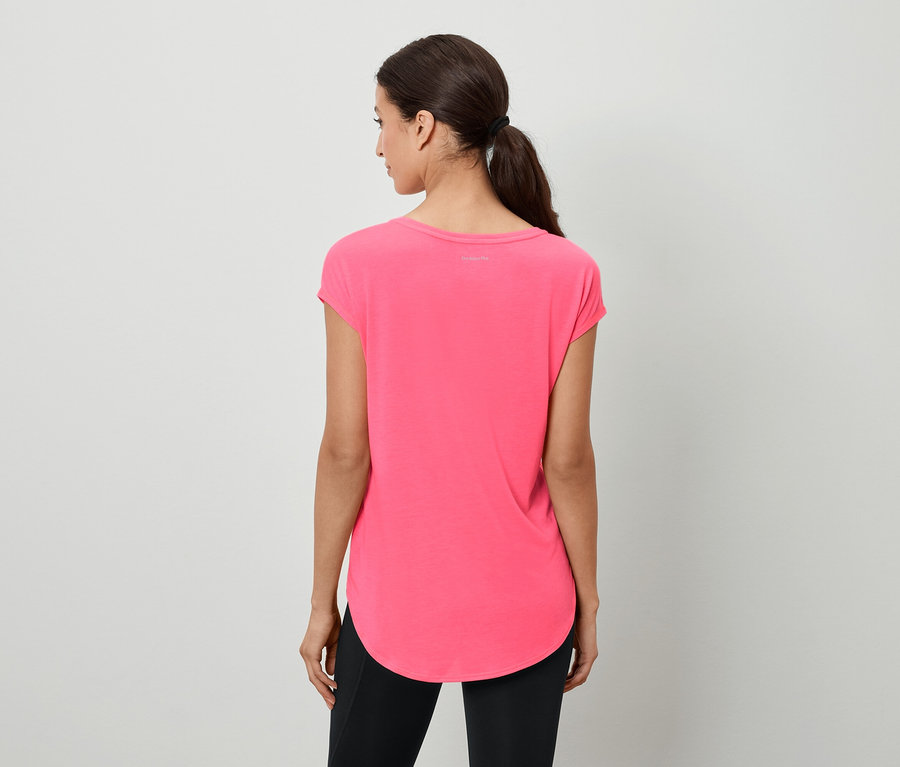 Frau mit braunen Haaren, die zu einem Pferdeschwanz zusammengebunden sind, steht mit dem Rücken zur Kamera und trägt ein rosafarbenes T-Shirt und schwarze Leggings.