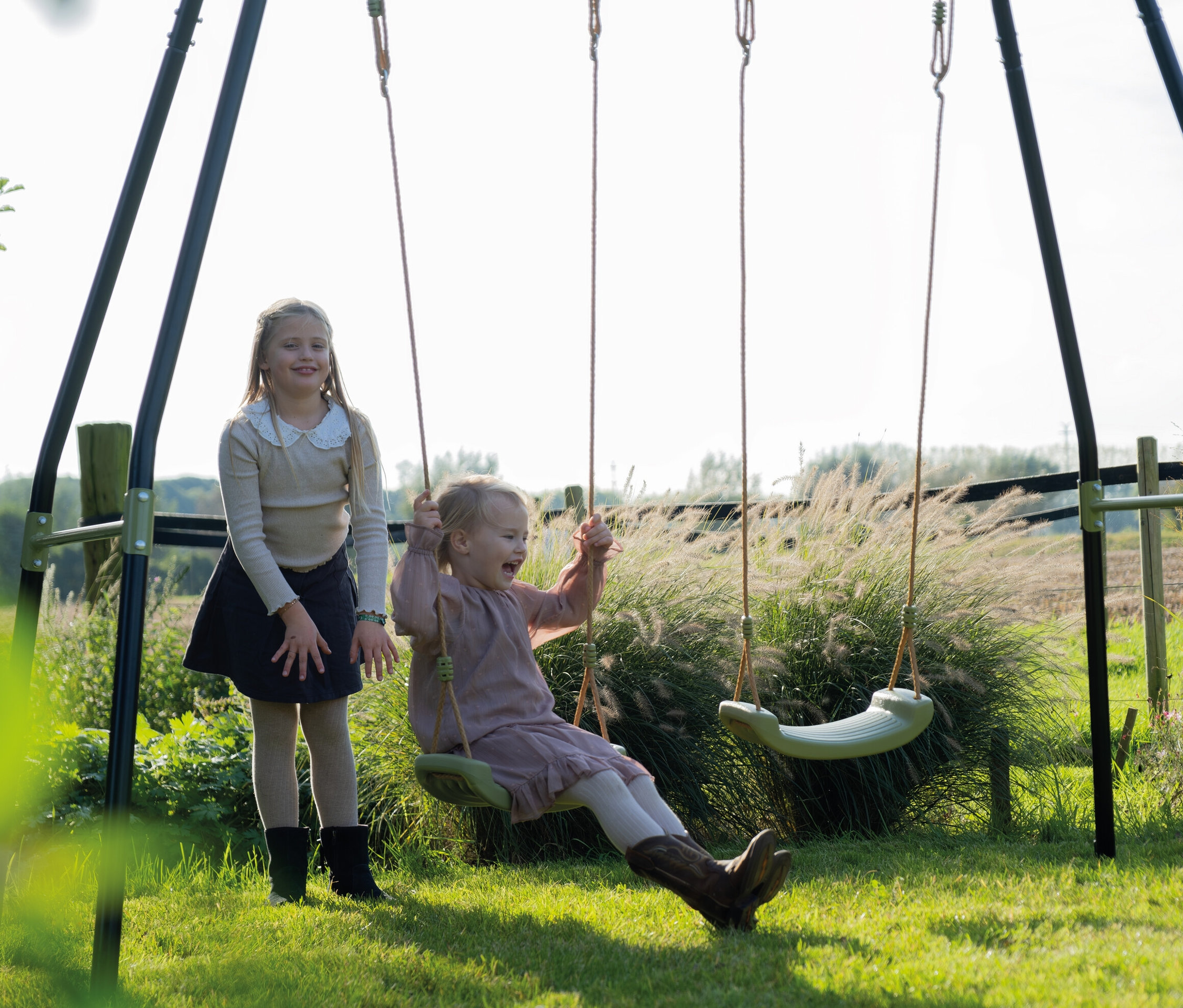 Zwei Mädchen draußen mit einer EXIT Doppelschaukel »Ivy«.