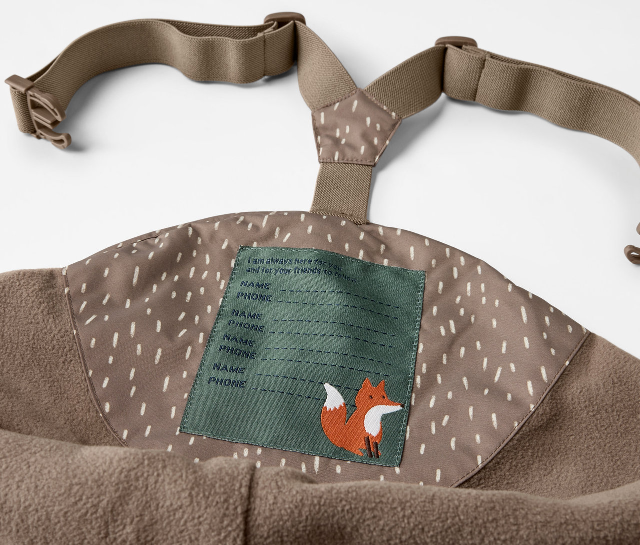 Detail der Kinder-Thermo-Regenhose mit Latz und Bär-Print, mit Namensschild und Fuchsabbildung.