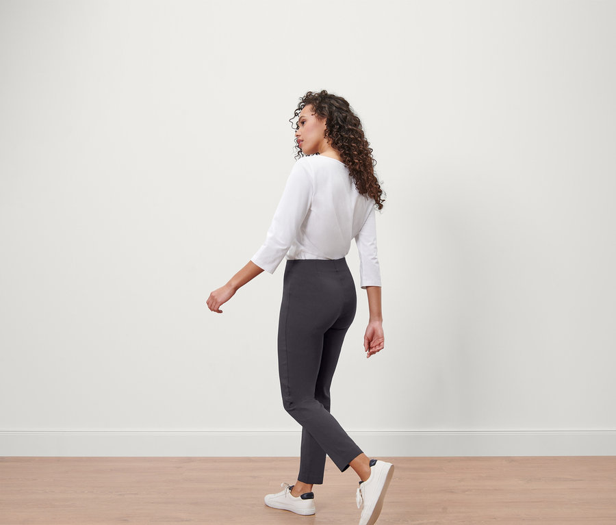 Frau in weißem Oberteil und grauer Stretchhose.