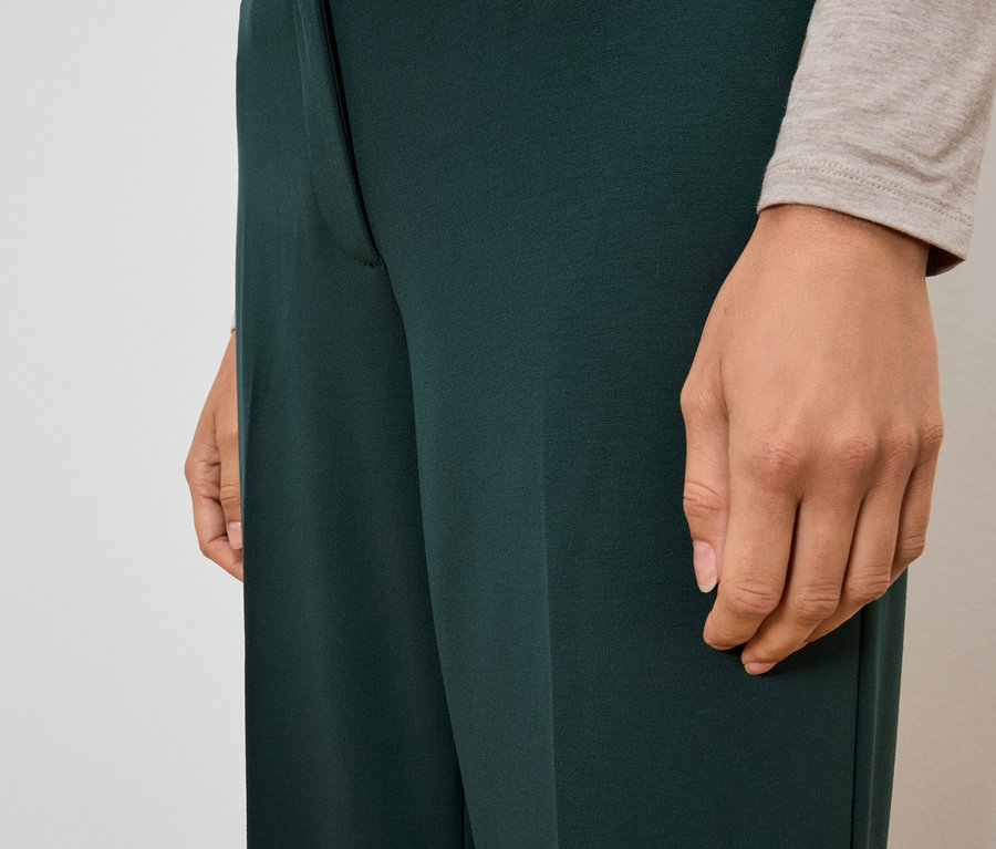 Detailaufnahme einer Frau, die eine dunkelgrüne Hose trägt.
