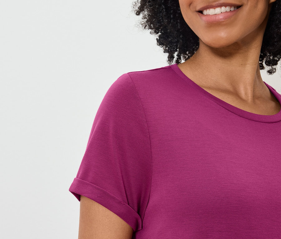 Detailaufnahme einer Frau mit lockigem Haar, die ein purpurrotes T-Shirt trägt.