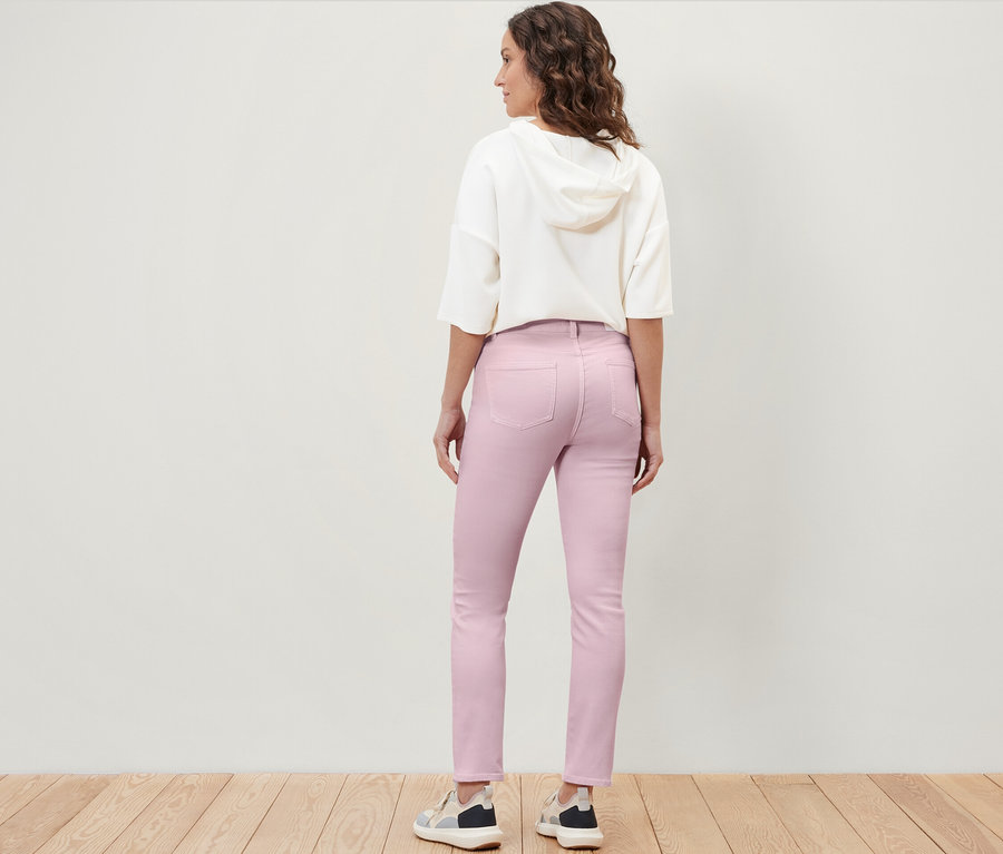 Eine Frau steht mit dem Rücken zur Kamera und trägt eine farbige Jeans im Schnitt „Emma“.