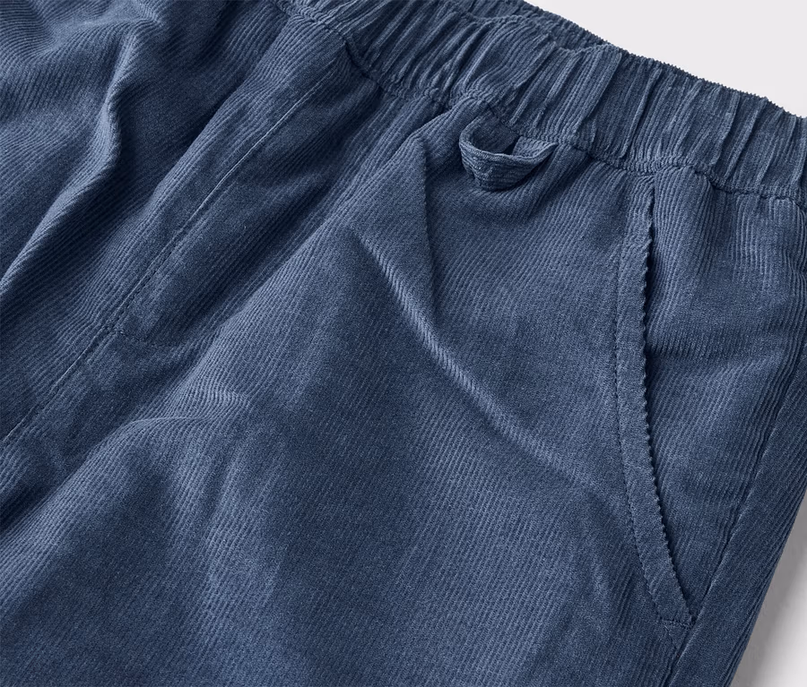 Nahaufnahme einer marineblauen Kordhose mit elastischem Bund und einer Seitentasche.