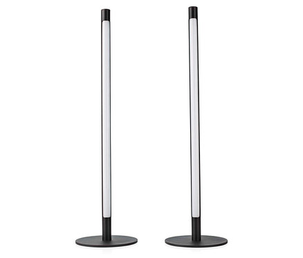Zwei schlanke, schwarze Stehlampen mit runden Sockeln und einem leuchtenden, weißen Stab in der Mitte vor einem weißen Hintergrund.