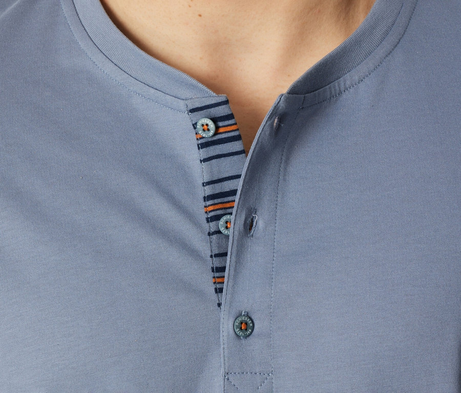 Nahaufnahme eines Mannes, der ein blaues Poloshirt mit Knöpfen und gestreiftem Detail trägt.