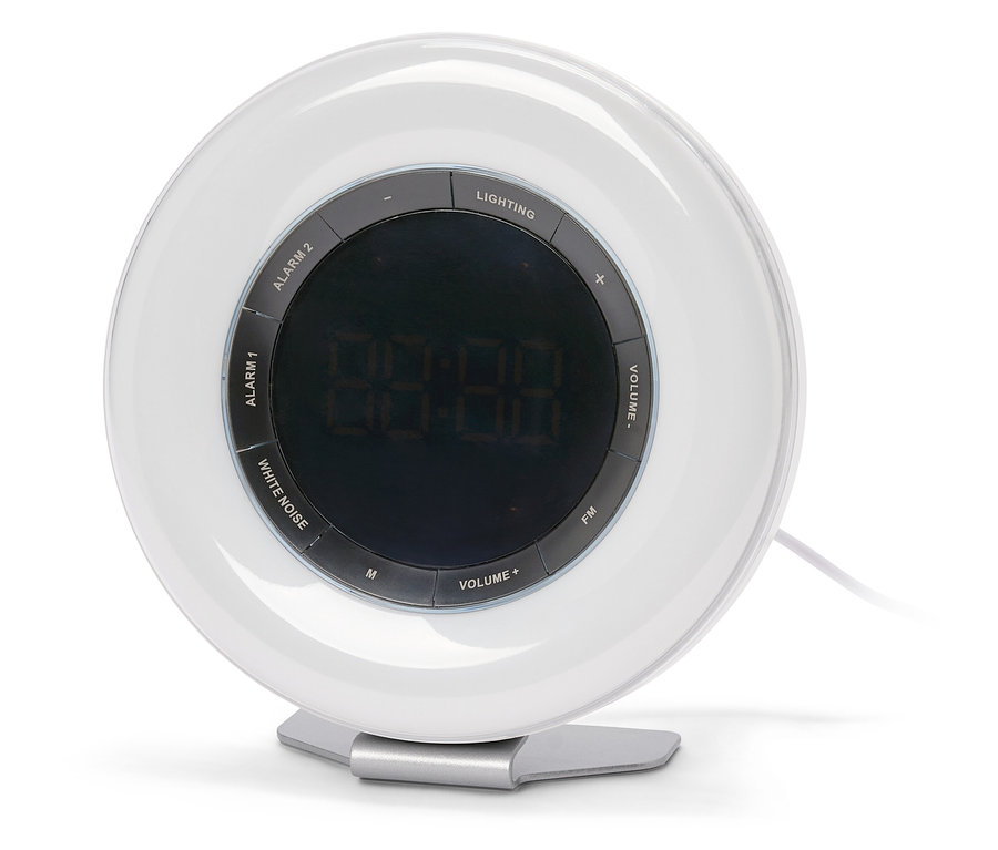 Runder, weißer Wecker mit digitaler Anzeige, der auf einem silbernen Ständer steht. Um das Display herum befinden sich Tasten für Beleuchtung, Alarm, Lautstärke und FM-Radio.