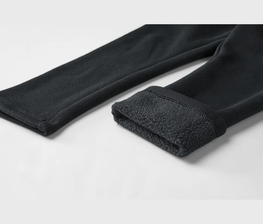 Nahaufnahme einer schwarzen Hose, ein Bein hochgekrempelt, um ein weiches, dunkles Fleecefutter zu zeigen.