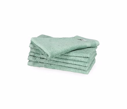Stapel von sechs salbeigrünen SCHÖNER WOHNEN-Kollektion Cuddly Gästehandtüchern auf weißem Hintergrund. Das oberste Handtuch liegt leicht schräg.
