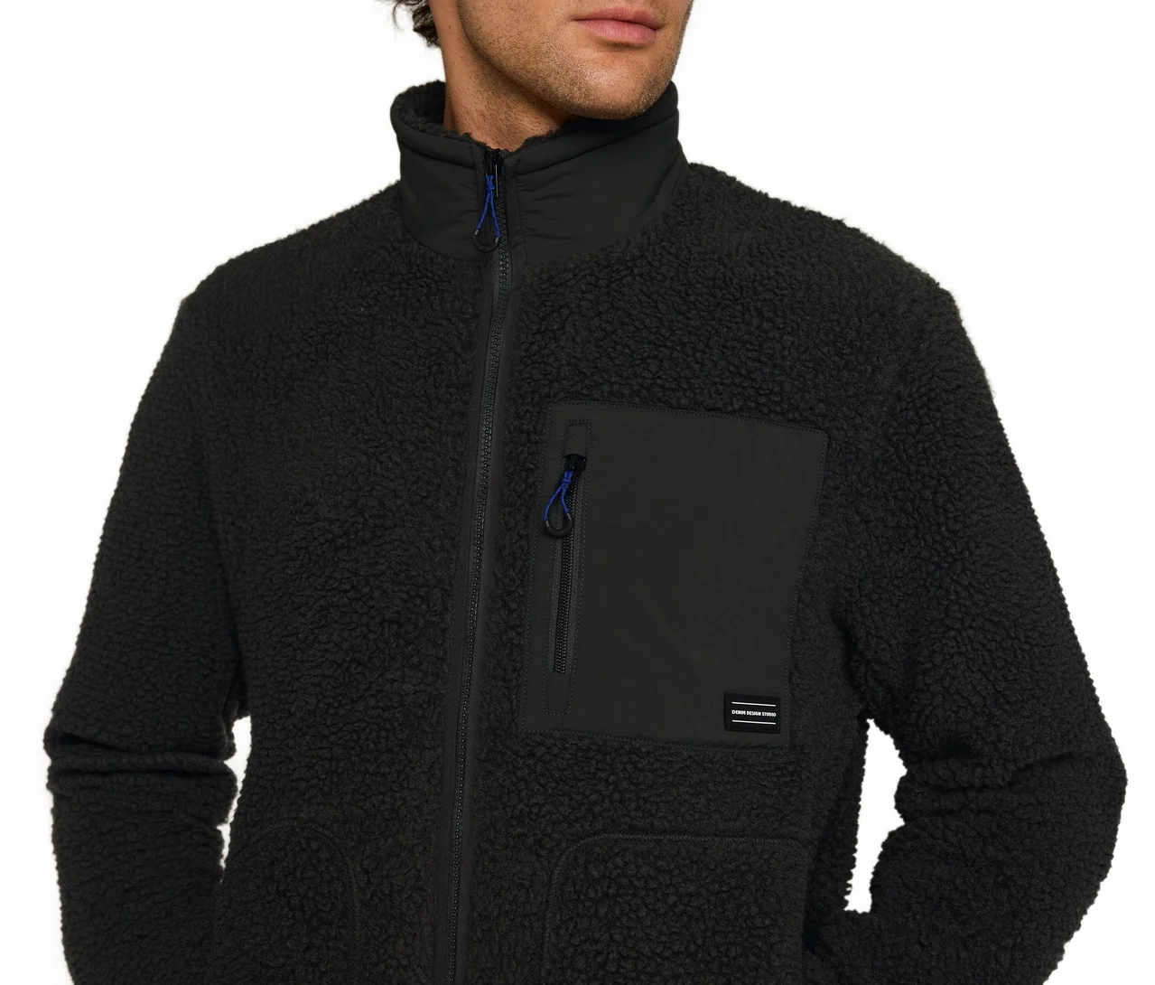 Mann trägt eine schwarze, texturierte Fleecejacke mit Stehkragen und einer Reißverschlusstasche auf der Brust mit blauem Zugband.