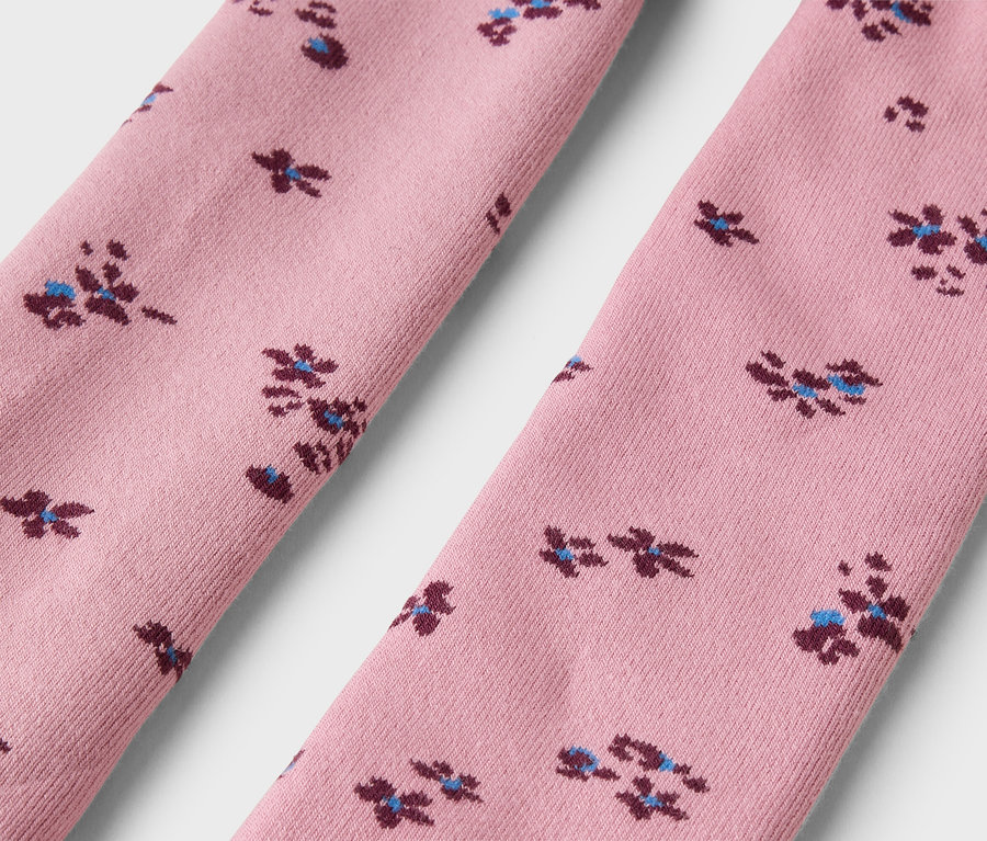 Zwei rosafarbene Stoffteile, möglicherweise Socken oder Strumpfhosen, mit einem sich wiederholenden Muster aus kleinen dunkelroten und hellblauen Blumen.