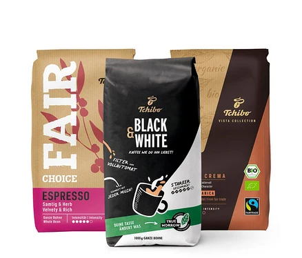 Drei Kaffeepackungen verschiedener Marken und Farben. Die Packung links ist braun mit der Aufschrift FAIR CHOICE ESPRESSO. In der Mitte befindet sich eine schwarz-weiße Packung mit der Aufschrift Tchibo Black & White. Die Packung rechts ist braun mit der Aufschrift Tchibo Vista Collection. Das "Probierset \"Für jeden Geschmack\" - 3 x 1 kg Ganze Bohne" ist sichtbar.