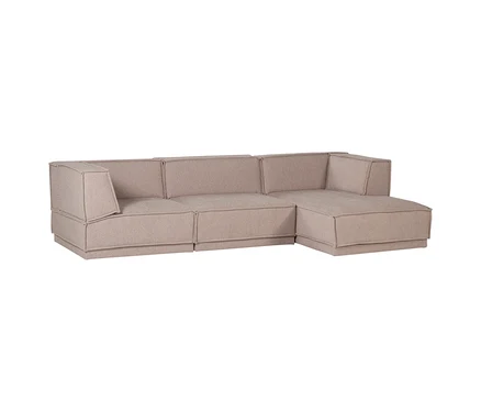 Ein hellbeiges, L-förmiges Modulsofa mit sichtbaren Nähten und einer Chaiselongue auf der rechten Seite.